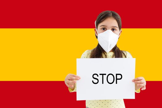Masked little girl looking at the camera on flag Spain background. The concept of attention to the worldwide spread of the coronavirus worldwide. Coronavirus, virus in Spain.