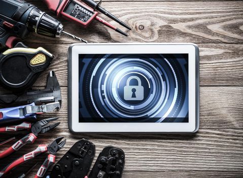 Tablet pc with security concept on screen and industrial tools around