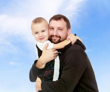 Happy family. Dad and son hug each other.On the background of summer blue sky and fluffy clouds.