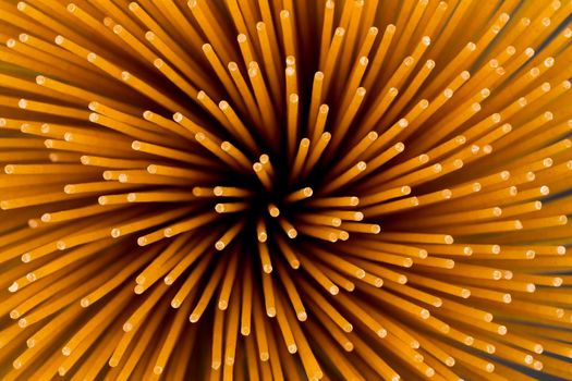 Flower of whole wheat spaghetti gathered in a bunch, view from top on stone plate