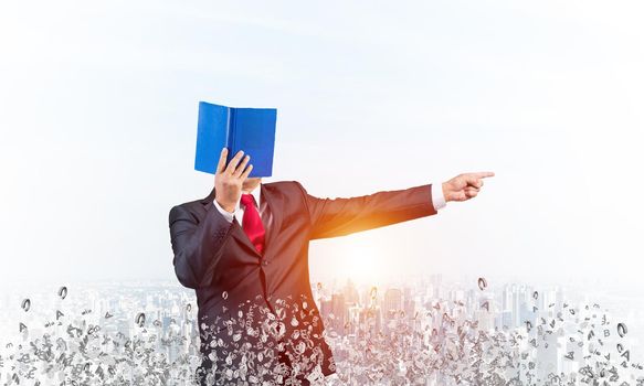 Businessman covered his face with organizer and finger pointing side. Man in business suit and tie standing on city background with flying various letters. Education and professional knowledges.