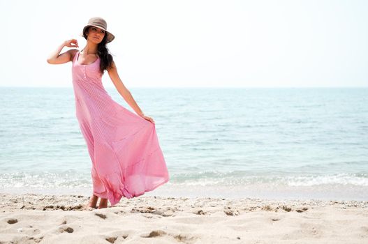 Portrait of a beautiful woman with long pink dress on a tropical beach