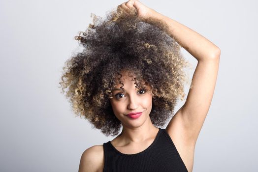 Young black woman with afro hairstyle smiling. Girl wearing black dress. Studio shot.