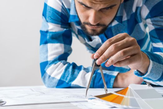Man measuring with compass divider on construction blueprint. Architect workplace with technical drawing. Architecture studio concept with design project. Professional building and engineering.