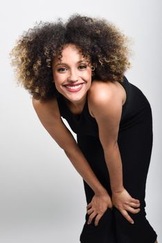 Young black woman with afro hairstyle smiling. Girl wearing black dress. Studio shot.