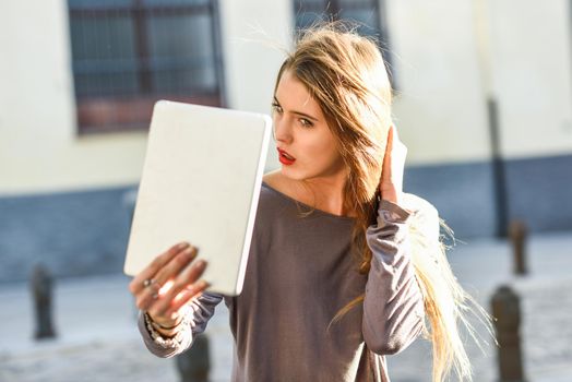 Young woman self looking at tablet in urban background