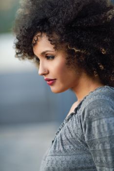 Young mixed woman with afro hairstyle standing in urban background. Black girl wearing casual clothes.