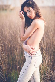 Fashion photograph of young sensual woman in jeans, in nature