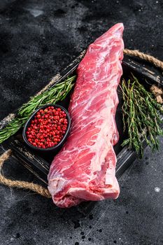 Raw veal calf short spare rib meat with thyme and rosemary. Black background. Top view.