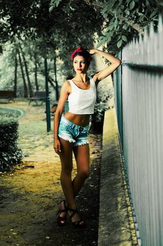 Portrait of a pin-up girl. American style, in a garden, wearing jeans and t-shirt