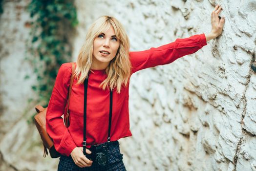 Attractive young blond woman taking photographs with an old slr camera in a beautiful city.