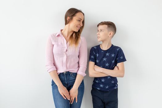 Charming young mother and a cute positive son are happy looking at each other while standing in the new living room after the move. The concept of good family relationships and relocation