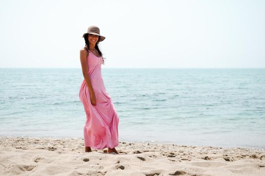 Portrait of a beautiful woman with long pink dress on a tropical beach