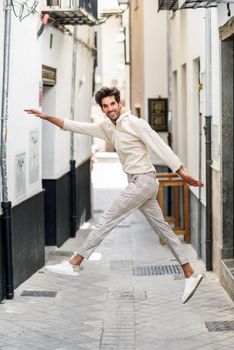 Young funny man jumping in the street. Attractive Guy wearing casual clothes in urban background.