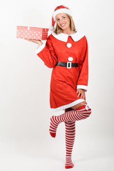 Blonde woman in Santa Claus clothes smiling with gift box in her hands. Young female with blue eyes wearing striped socks, isolated on white
