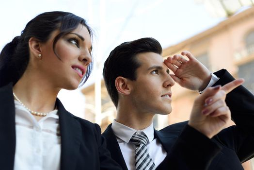 Portrait of attractive businessman and businesswoman looking at something interesting. Couple working.