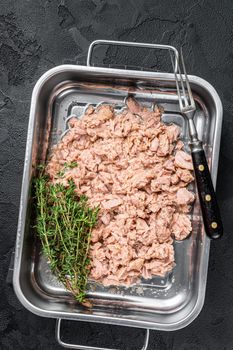 Tuna canned fish with olive oil in a tray . Black background. top view.