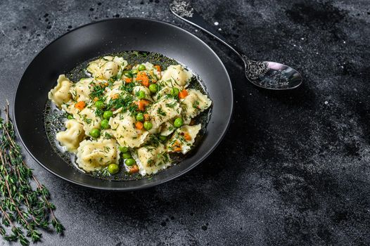 Dumplings Soup with Ravioli pasta in a bowl with greens. Black background. Top view. Copy space.