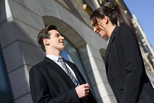 Attractive business people talking outside of company building. Couple working.