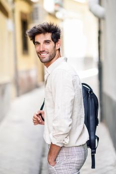 Young man sightseeing enjoying the streets of Granada, Spain. Male traveler carrying backpack in urban background.