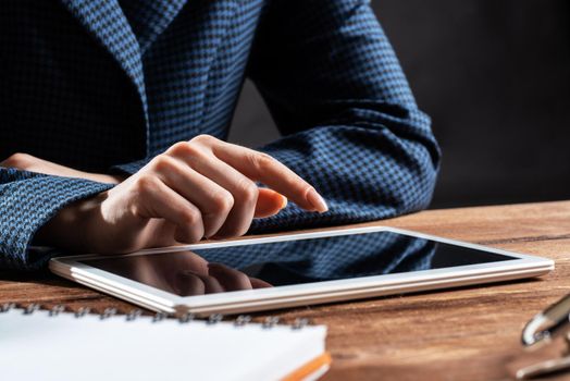 Businesswoman using tablet computer at desk. Close up woman hand pointing on touchscreen. Online stock trading and financial analytics. Digital technology in strategy planning and company management
