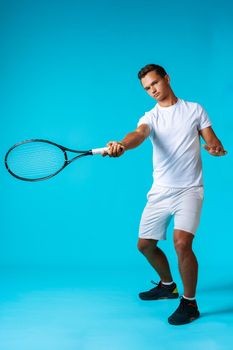 Full length studio portrait of a tennis player man on blue background close up