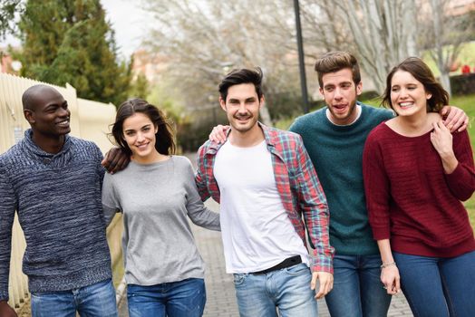 Group of multi-ethnic young people having fun together outdoors in urban background. group of people walking together