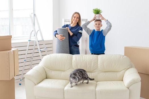 Young cute mother and son are happy about the move to new house holding a lop-eared scottish cat and a pot of greens in their hands. Concept of housewarming and family space extensions