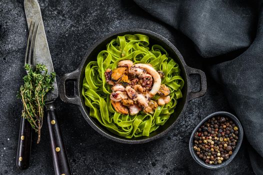 Green spinach fettuccine pasta with cheese and seafood, shrimp, squid, octopus, mussel. Dark background. Top view.