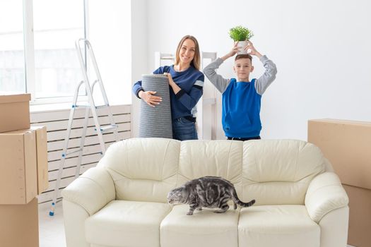 Young cute mother and son are happy about the move to new house holding a lop-eared scottish cat and a pot of greens in their hands. Concept of housewarming and family space extensions