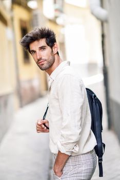 Young man sightseeing enjoying the streets of Granada, Spain. Male traveler carrying backpack in urban background.