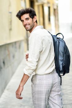 Young man sightseeing enjoying the streets of Granada, Spain. Male traveler carrying backpack in urban background.