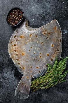 Raw flounder flatfish fish on marble board with thyme. Black background. Top view.