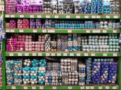 Sale of Christmas toys in the supermarket. Balls of red colors for the Christmas tree on the supermarket shelves. Christmas toys for sale in the store. Variety of red glass balls