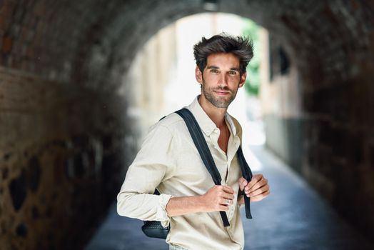 Young man sightseeing enjoying the streets of Granada, Spain. Male traveler carrying backpack in urban background.