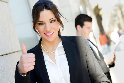 Portrait of an attractive businesswoman showing thumb up sign. Couple working.