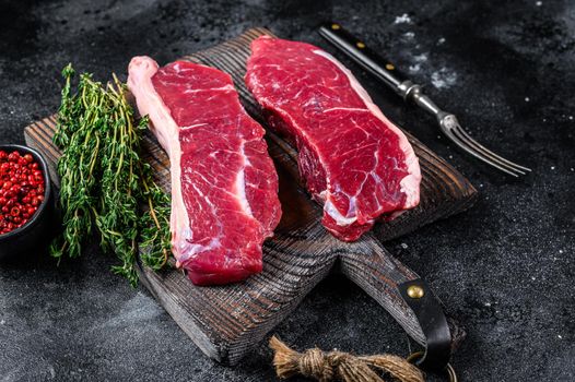 Raw marbled beef meat sirloin steak. Black background. Top view.