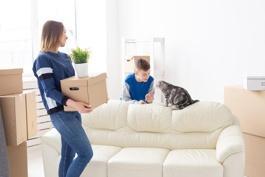 Slim positive young mother and a cute boy son arrange things and communicate with their scottish fold cat. Housewarming and relocation concept.