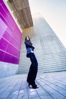 Wide-angle photo of a woman wearing blue suit posing near a modern building. Fashion concept.