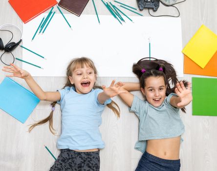 Cute children are painting and smiling while lying on the floor at home