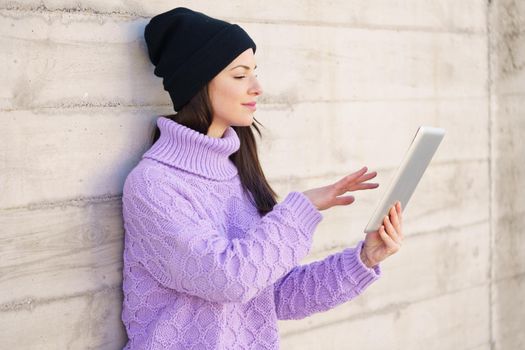 Female student in her twenties using digital tablet outdoors. Lifestyle concept.