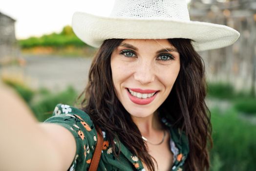 Beautiful hiker young woman, wearing flowered shirt, taking a selfie photograph outdoors