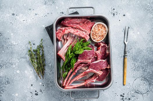 Uncooked Raw lamb, mutton chops in a steel kitchen tray. Gray background. Top view.