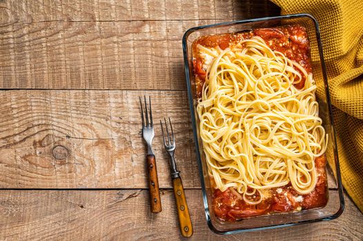 Oven baked feta Spaghetti pasta in baking dish. Wooden background. Top view. Copy space.