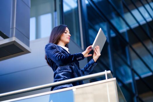 Business woman wearing blue suit using digital tablet in an office building. Lifestyle concept.