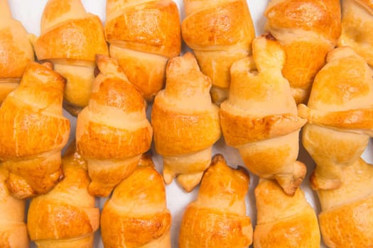 Fresh homemade baked goods. Croissants in heap background. Buns on the counter at the bakery, close up.