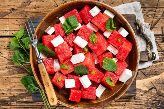 Summer Watermelon Salad with feta cheese and mint in a wooden plate. Wooden background. Top view.