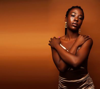 pretty young african american woman with braids posing cheerful gesturing on brown background, lifestyle people concept close up