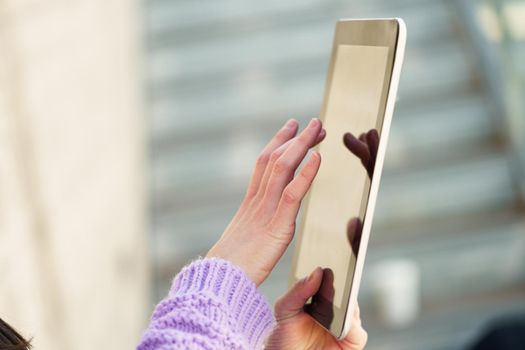 Detail of unrecognizable woman using digital tablet outdoors. Lifestyle concept.