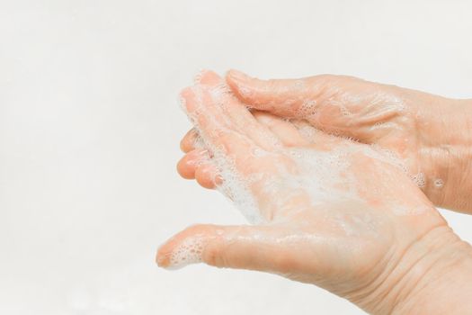An adult woman's hands lathered with soap, close-up. Hand washing and domestic hygiene concept.